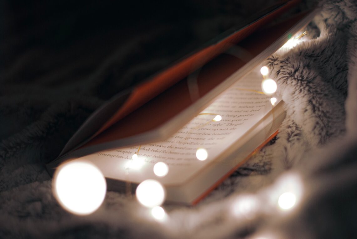 Symbolbild: Aufgeschlagenes Buch umschlungen von einer Lichterkette cc Jenna Velez